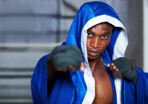 Black man, portrait and boxing champion in robe getting ready for fight, challenge or sports competition at gym. Serious African male person, fighter or professional boxer in MMA, match or game start