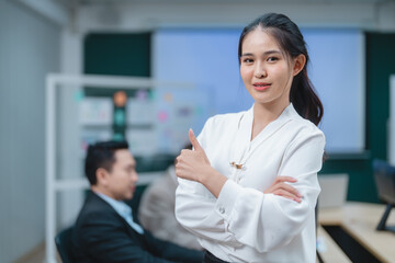 Obraz premium Happy confident smiling young professional Asian business woman corporate leader, Japanese female employee or company sales marketing manager standing arms crossed in office, cute girl portrait