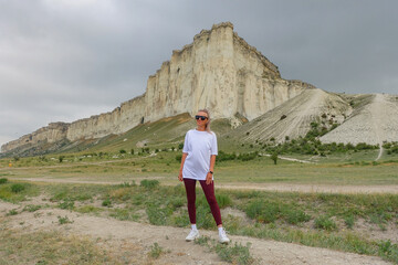 Fototapeta premium A woman on the background of a landscape view of the White Mountain in the Eastern Crimea. Photos of the Crimean peninsula in summer, the white rock of Ak-Kaya, the Biyuk-Karasu river