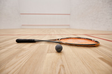 ball and racquet on floor inside of indoor squash court, motivation and determination concept