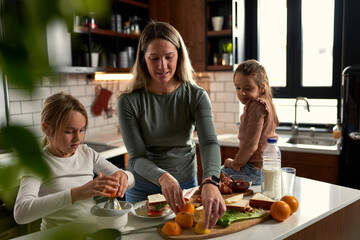  Laughter echoes in the kitchen as mother and daughters squeeze oranges, creating a refreshing touch to their delightful breakfast.