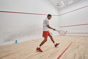 dynamic african american sportsman playing squash inside of court, challenge and motivation