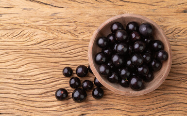 Jabuticabas on a bowl over wooden table with copy space