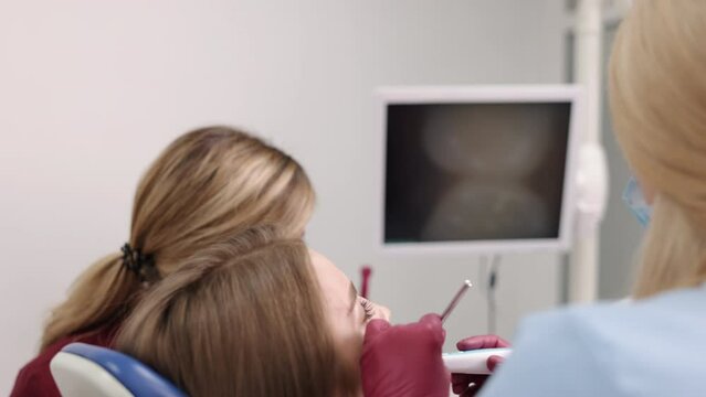 Young patient, dental imaging, dental check. Professional in field of dentistry is conducting thorough examination of young woman's mouth using intraoral camera.