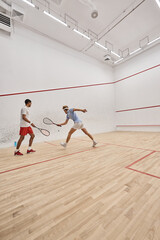 Fototapeta na wymiar interracial athletic men in sportswear playing together inside of squash court, motivation