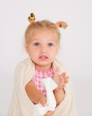 Sweet little girl blows her nose into a handkerchief