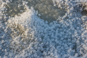 Thick layers of ice on the river cover large beautiful snowflakes during frosts