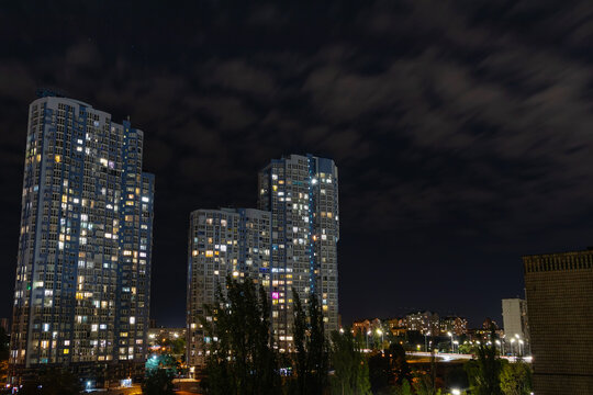 Evening cityscape with high multi-storey residential buildings. Light from the windows of modern buildings in the city on a summer night © Vlad Kazhan