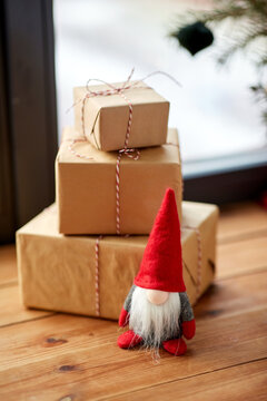 holidays, new year and celebration concept - close up of christmas gifts, gnome and fir branches on window sill at home