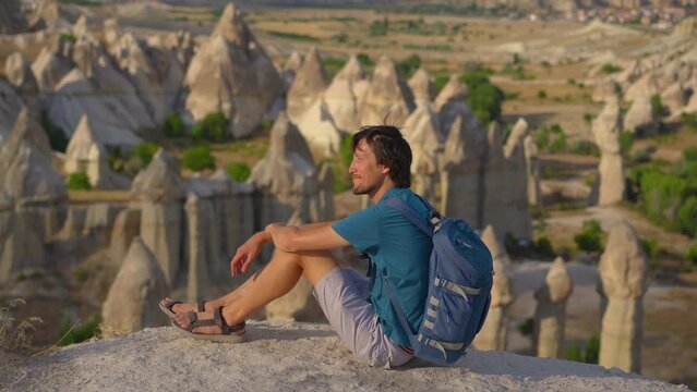 Embark on a journey as a young man explores the enchanting Goreme National Park in Cappadocia, Turkey. Marvel at the surreal rock formations that characterize this unique landscape.