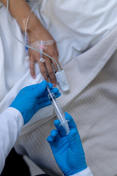 Hand of female patient with iv drip in bed in hospital room