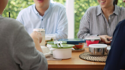 Gen Z asia people group save the planet earth relax eating food go green meal eco friendly glass lunch box reduce plastic waste free water bottle at table SDGs office. ESG net zero happy staff team.