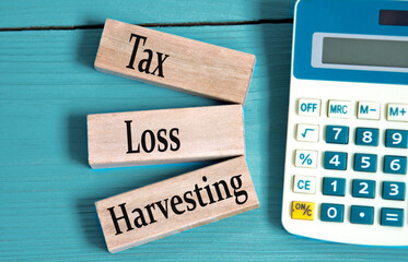 TAX LOSS HARVESTING - words on wooden blocks with a calculator in the background