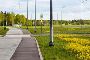 An asphalt bike path running along a deserted pedestrian sidewalk