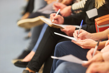 Audience writing in document at event in auditorium