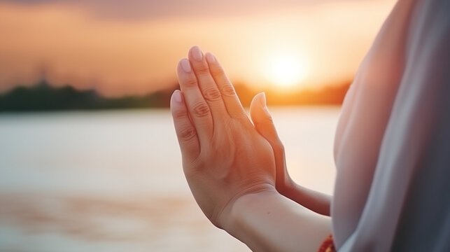 Woman practicing mindfulness meditation in serene sunset by the water with a focus on hands in prayer position