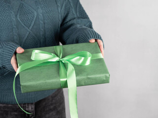 The girl holds in her hand a green gift box with a gift ribbon. Holidays concept.