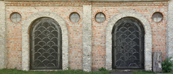 Very old solid door in brick stone wall of castle or fortress of 18th century. Full frame wall with...