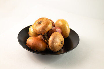 Onions are piled on a black plate on a white background