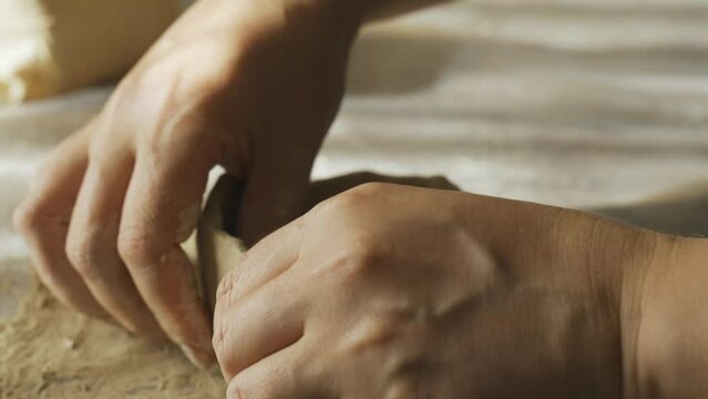 A woman shapes a gray clay plate with her hands, close-up. Making crafts from clay. Hobbies and creativity.
