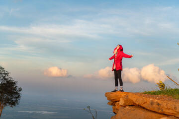 Obraz premium Portrait of a beautiful young woman in red coat on the background of blue sky