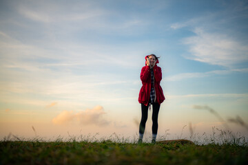 Portrait of a beautiful young woman in red coat on the background of blue sky