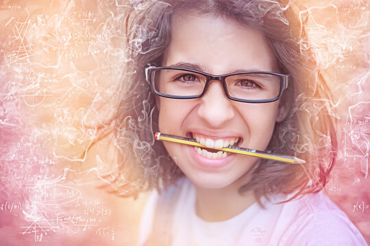 Portrait of a schoolgirl fed up with holding a pencil between her teeth