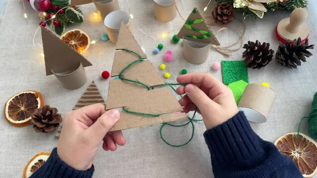 Handmade Christmas trees decoration. Close-up of children's hands decorating with twine. Zero waste concept.