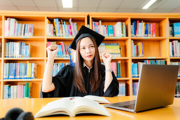 Excited Asian female university graduate celebrates successful graduation via video on laptop computer.