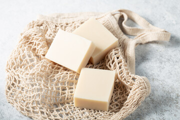 Natural handicraft soap bars beige color on mesh bag background close-up