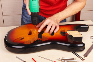 Guitar master drills holes for installing tremolo in guitar body.
