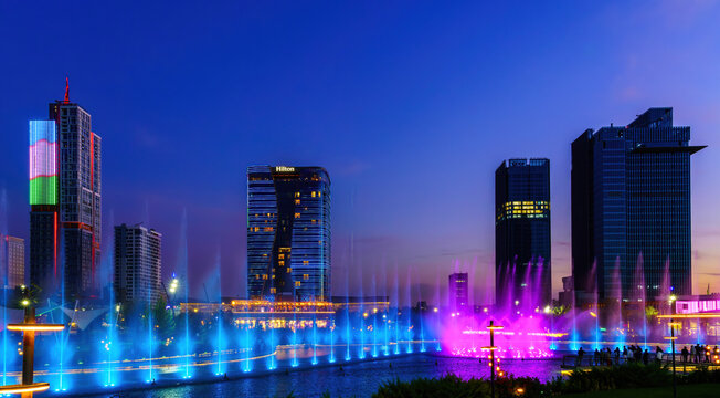 Uzbekistan, Tashkent - September 29, 2023: A fountain with laser illumination and light music in Tashkent City Park at nighttime and scyscrapers.