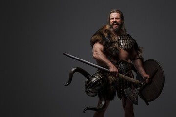 A fearless Viking warrior with a majestic beard adorned in fur and light armor, carrying an axe and...
