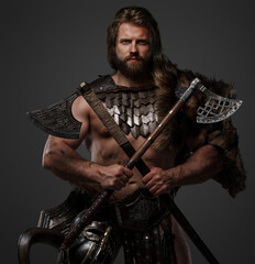 A rugged bearded Viking warrior dressed in fur and lightweight armor, with a helmet attached to his...