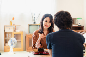 ドラマのようなレトロな雰囲気の食卓でごはんを食べる若い夫婦
