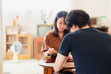 ドラマのようなレトロな雰囲気の食卓でごはんを食べる若い夫婦
