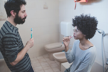 young multiethnic couple indoor bathroom brushing teeth