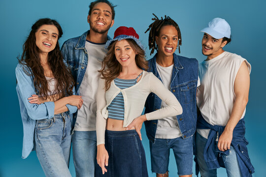 group portrait of interracial friends in casual wear smiling at camera on blue, street fashion