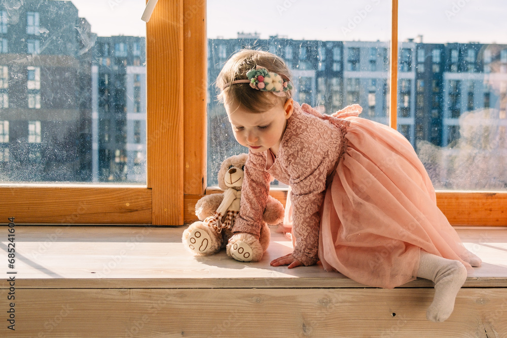 Wall mural little cute girl in dress near window