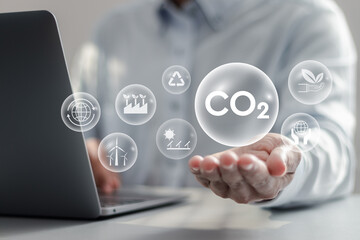 Businessman using laptop with reduce CO2 emissions icons on virtual screen for climate change to limit global warming and sustainable development and green business concept. - obrazy, fototapety, plakaty