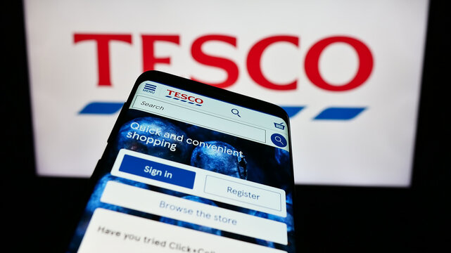Stuttgart, Germany - 11-17-2023: Mobile phone with website of British grocery retail company Tesco plc in front of business logo. Focus on top-left of phone display.