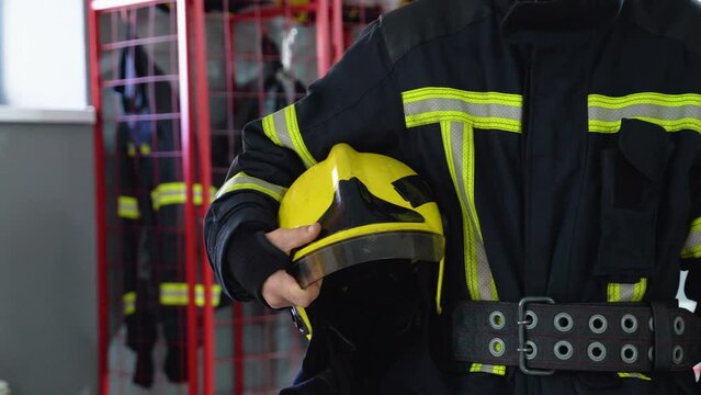 Fireman with hard hat in her hands standing at station, close up