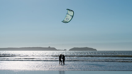 Silhouette of an unidentified couple getting ready to do kitesurfing at the beach of Essaouira,...