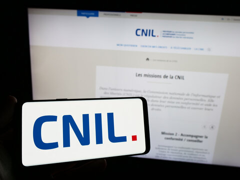 Stuttgart, Germany - 11-21-2023: Person holding smartphone with logo of Commission Nationale de l'Informatique et des Libert&eacute;s (CNIL) in front of website. Focus on phone display.