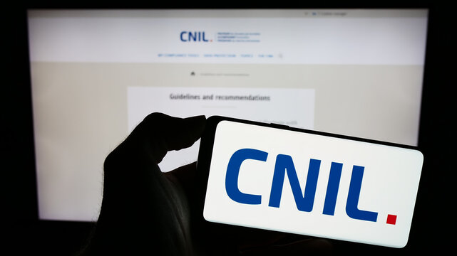 Stuttgart, Germany - 11-21-2023: Person holding mobile phone with logo of Commission Nationale de l'Informatique et des Libert&eacute;s (CNIL) with web page. Focus on phone display.