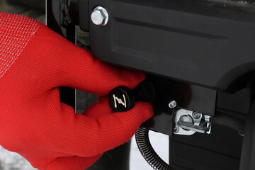 A man in red gloves closes the carburetor choke before starting a cold gasoline generator engine