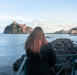 fantastico borgo di Ischia Ponte, Isola D'Ischia, visto da una prospettiva insolita, la ragazza ammira il paesaggio che ha di fronte invitando anche l'osservatore a fare lo stesso