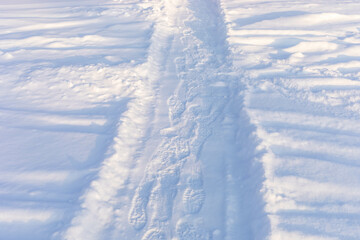 Snowy winter pathway with shoes prints. Human feet traces in snow. Hiking, local travel, staycation