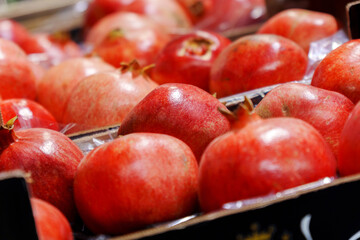 Pomegranates in the fruit department. Goods in the supermarket window. Buying fruit