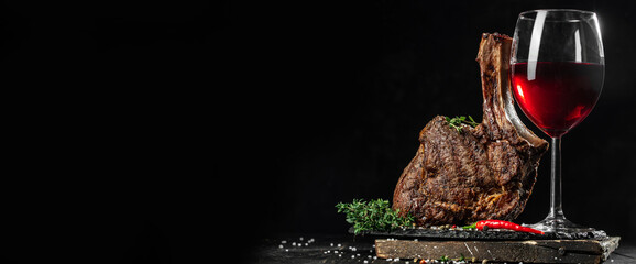 Grilled Tomahawk Steak on bone and glass of Red wine on a wooden board. Long banner format. copy space for text